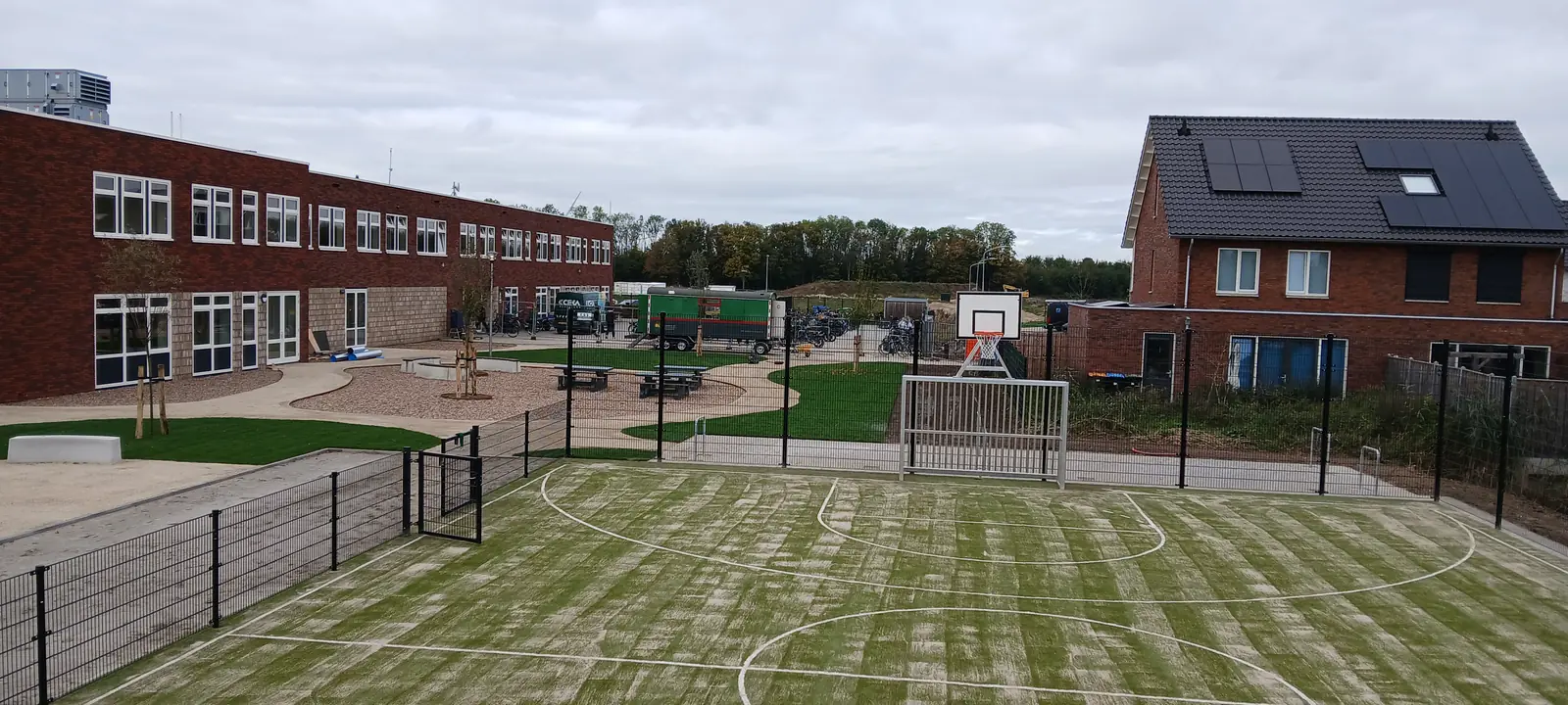 Aangelegd buitenterrein met kunstgrasveld, hekwerk en bestrating