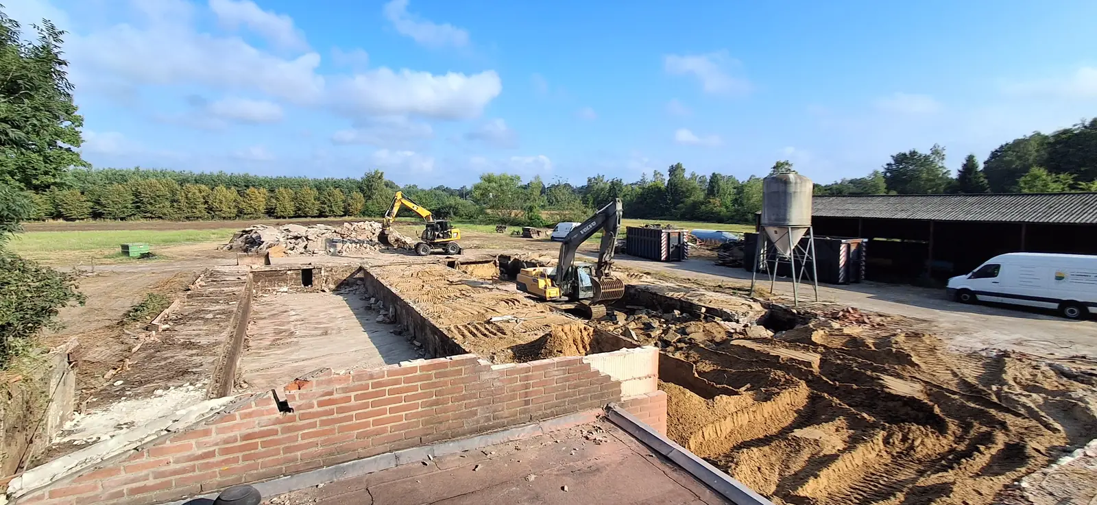 Sloop van een oude stal met graafmachines, vrijkomend puin wordt afgevoerd